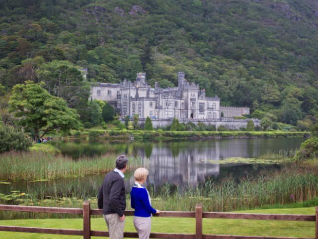 Couple stand looking towards Kylemore Abbey | Private tours of Ireland